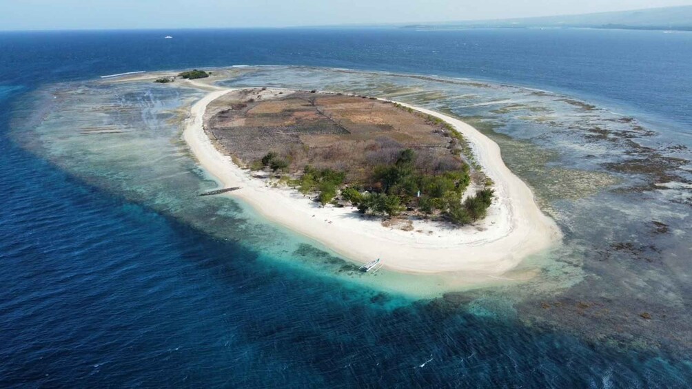 An aerial view of a small island with a sandy beach, surrounded by clear blue waters. 3