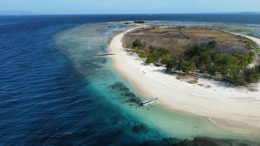A beach with clear turquoise waters, a boat anchored near the shore, and a small island with vegetation. 1