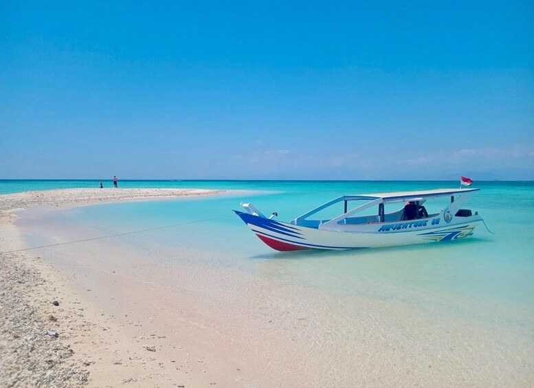 A boat on a sandy beach with clear turquoise water. 1