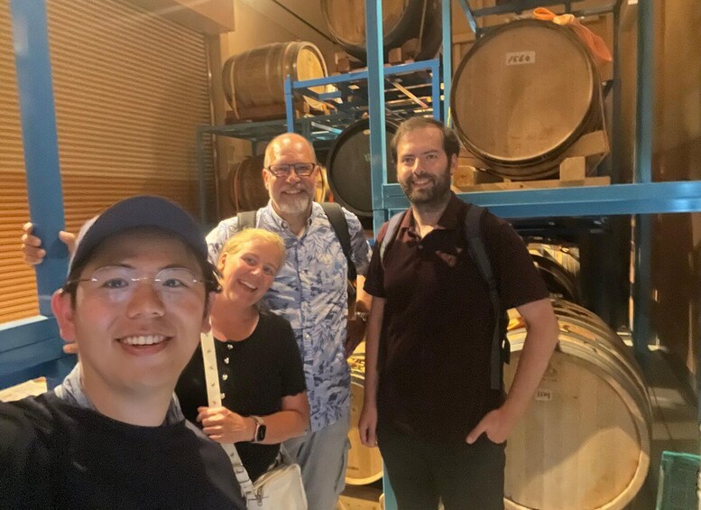A group of people standing in a storage area with large barrels. 3