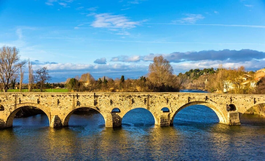A stone bridge with multiple arches over a river, surrounded by trees and buildings. 3