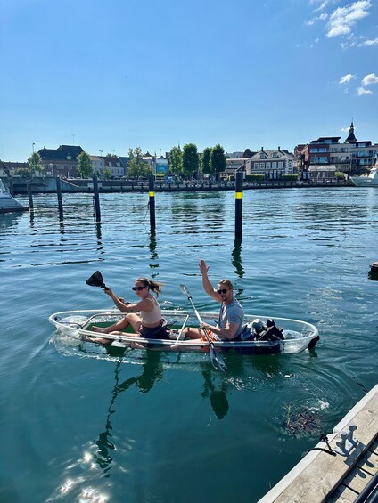 Two people in a small boat on a calm body of water, with buildings and a dock in the background. 5