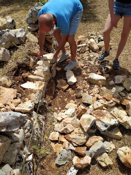 Two people working on a stone wall, surrounded by a rocky landscape. 5