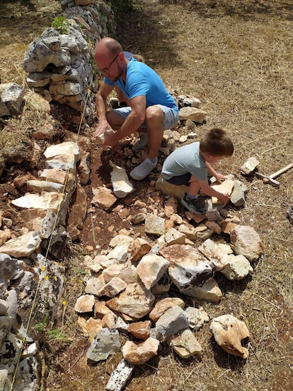 Two people engaged in a stone-moving activity outdoors. 3