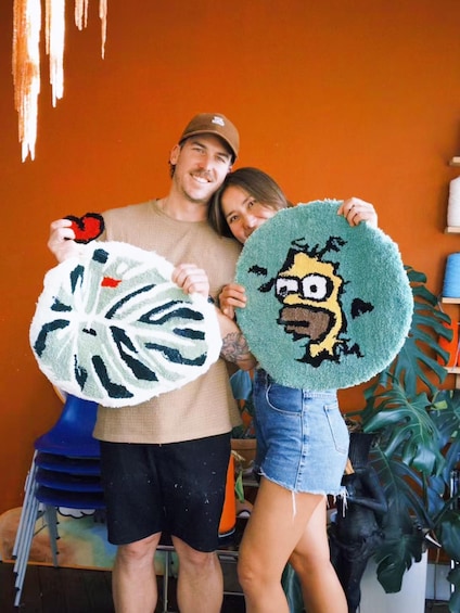 Two people holding circular rugs with cartoon characters. 5