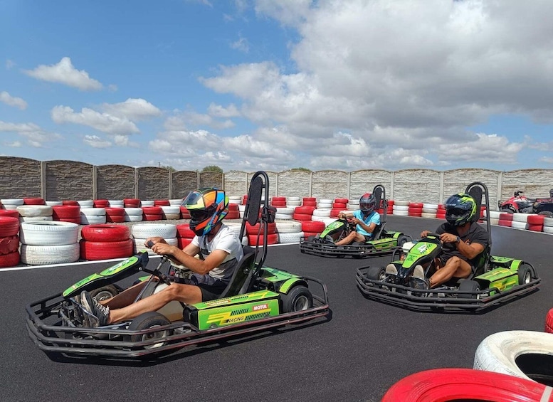 Three go-kart racers in a go-kart track with red and white barriers. 2