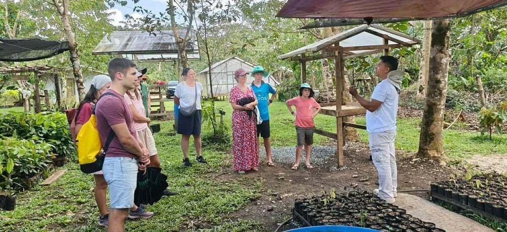 A group of people standing in a garden with a wooden structure and plants. 5