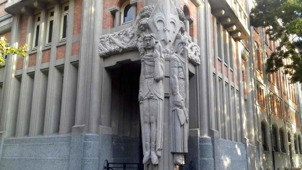 A building with a detailed stone facade and a large, ornate sculpture of a figure holding a child. 3