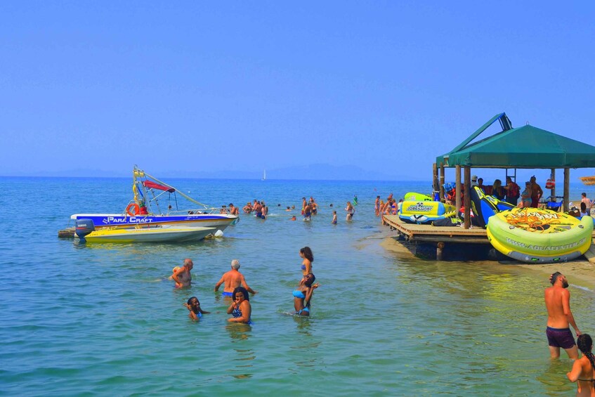 A beach with people swimming and a boat docked nearby. 5