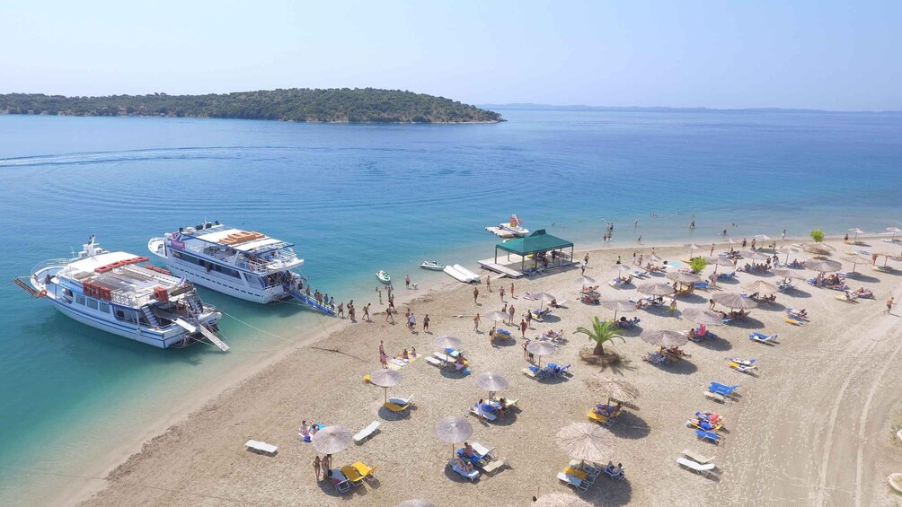A beach with people sunbathing and a boat docked near the shore. 4