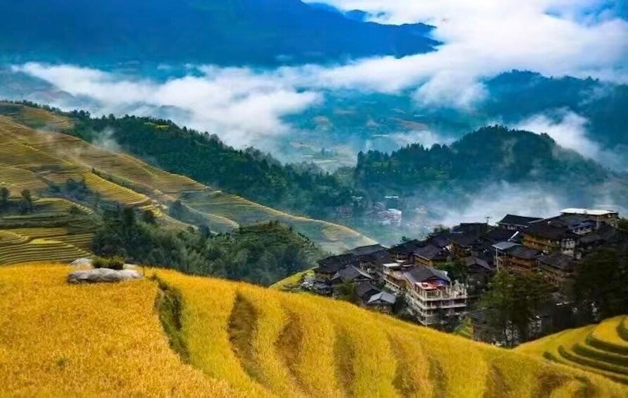 Terraced rice fields, a village with traditional houses, and a mountain range with clouds. 1