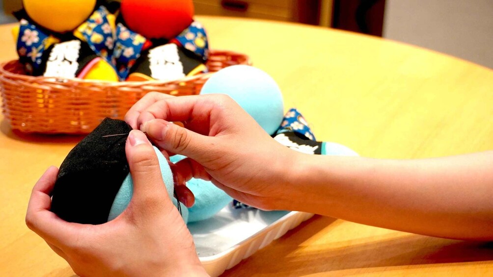 Hands holding a black object, possibly a piece of fabric, with a blue object in the background. 4