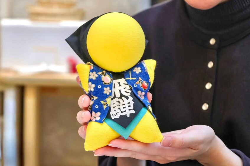 A person holding a yellow doll with a blue and black patterned cloth. 3