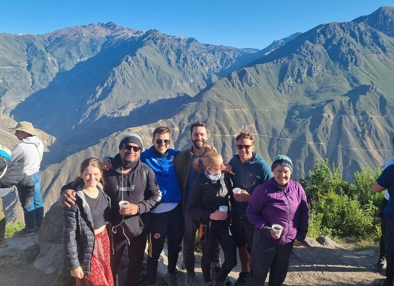 A group of people standing on a mountain trail with a mountainous landscape in the background. 2