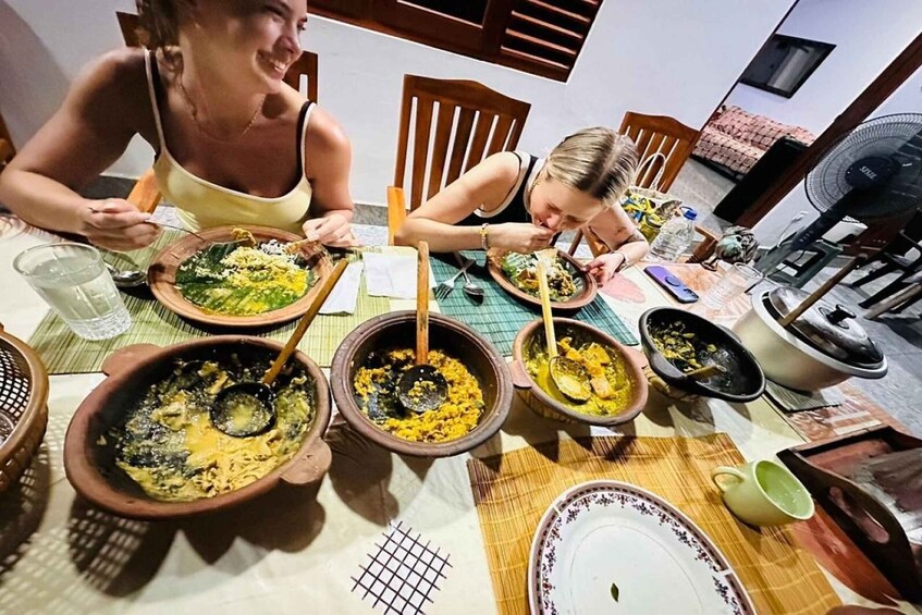 A group of people dining at a table with various dishes in clay pots. 3