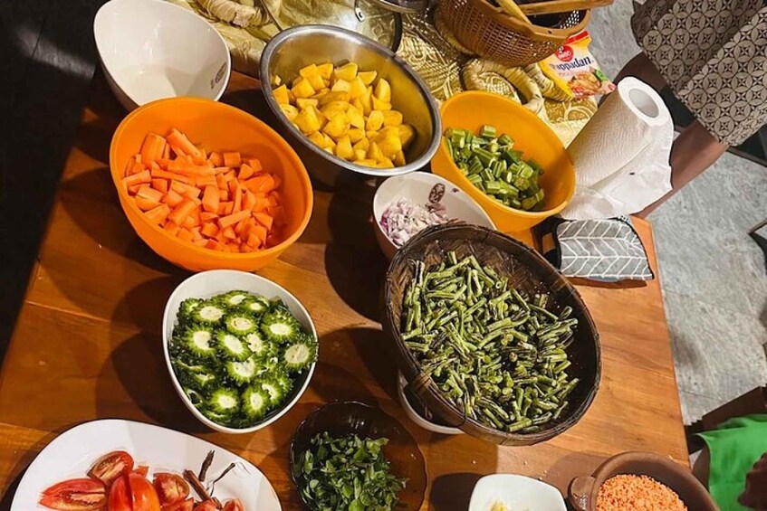 A table with various bowls of chopped vegetables including carrots, potatoes, and green beans. 5