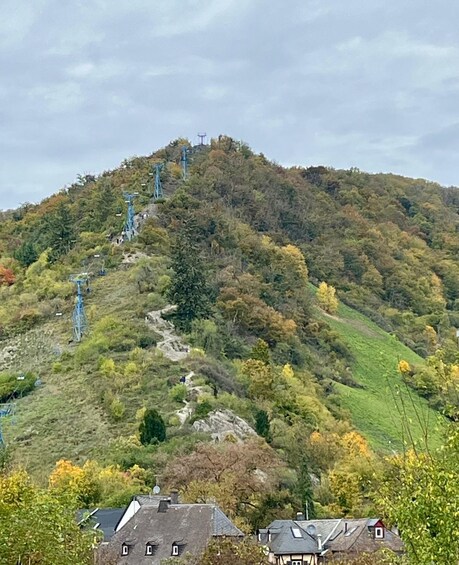 A hillside with a cable car system, houses at the base, and autumn-colored trees. 2
