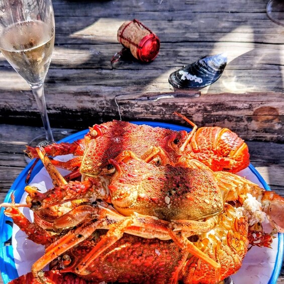 A large crab on a blue plate, a glass of white wine, and a corkscrew on a wooden table. 5