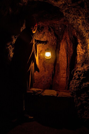 A person in a cave with a lantern. 3