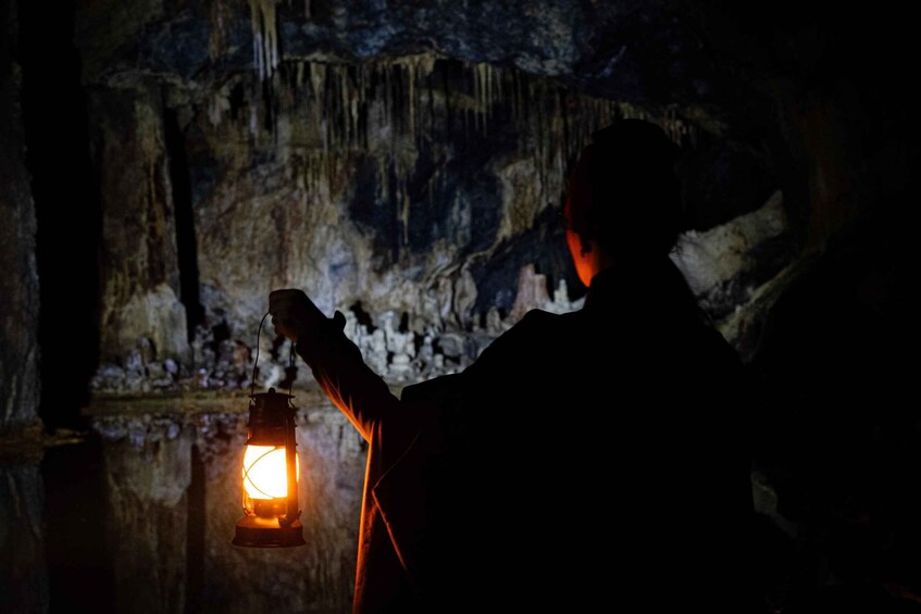A person holding a lantern in a cave with stalactites. 2