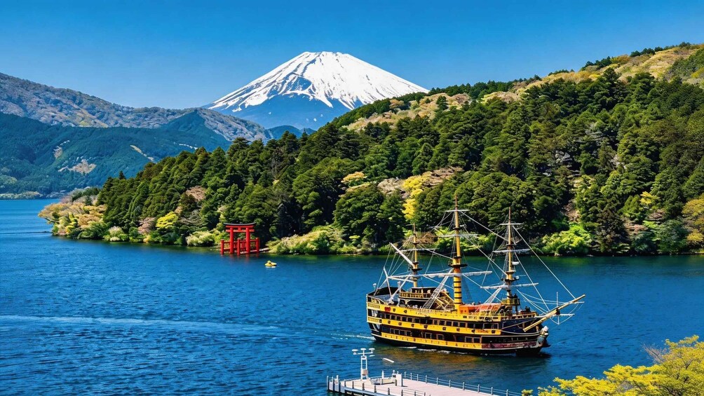 A traditional boat on a lake with a red torii gate and a snow-capped mountain in the background. 2