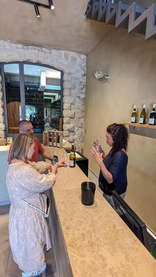 A bar with a stone wall, a counter, and wine bottles. 2