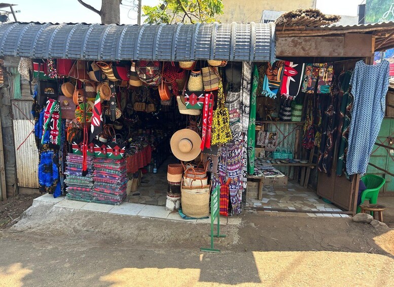 A small shop with a corrugated metal roof displaying various bags and textiles. 2