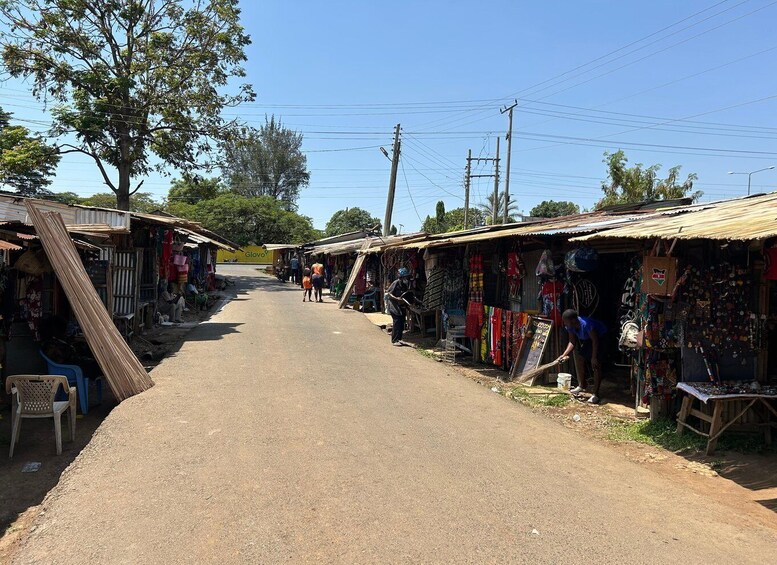 A rural street lined with small shops selling various goods, including textiles and accessories. 5
