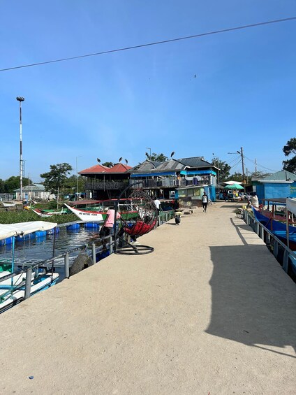 A riverside dock with boats, a covered structure, and a clear blue sky. 1