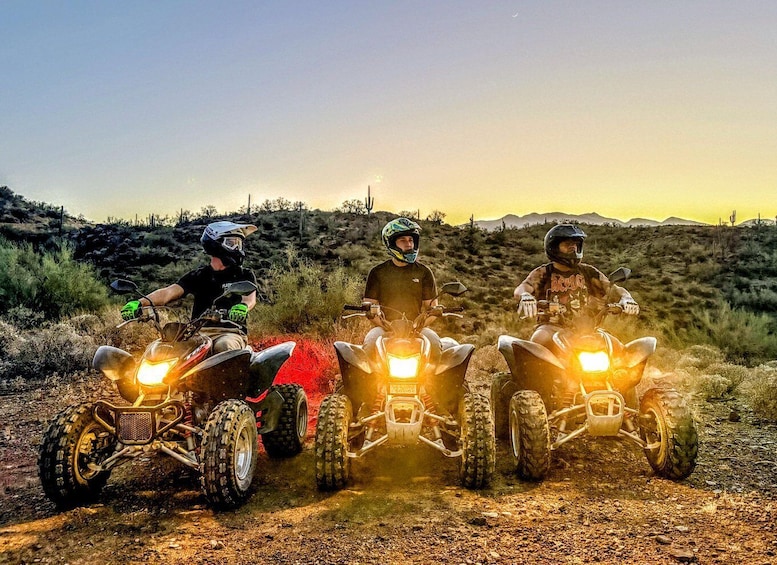 Three off-road vehicles with riders in helmets on a dirt trail. 1