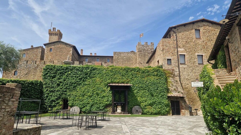 A courtyard with stone buildings, a green ivy-covered wall, and outdoor seating. 3