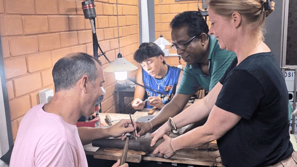 A group of people engaged in a woodworking activity, using tools on a wooden plank. 1