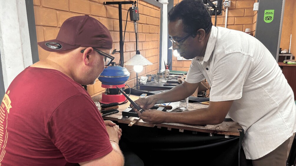 Two individuals engaged in a mechanical task, with tools and a workbench in a workshop setting. 3