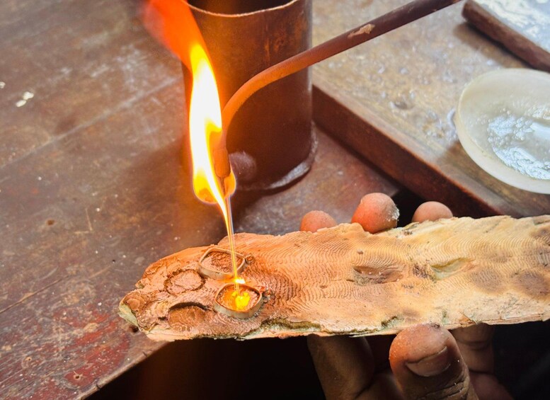A person holding a fish with a hole in its head, using a torch to light it. 2