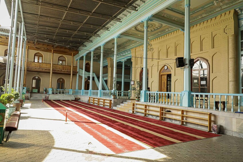An interior with a red carpet, blue railings, and a tiled floor. 4