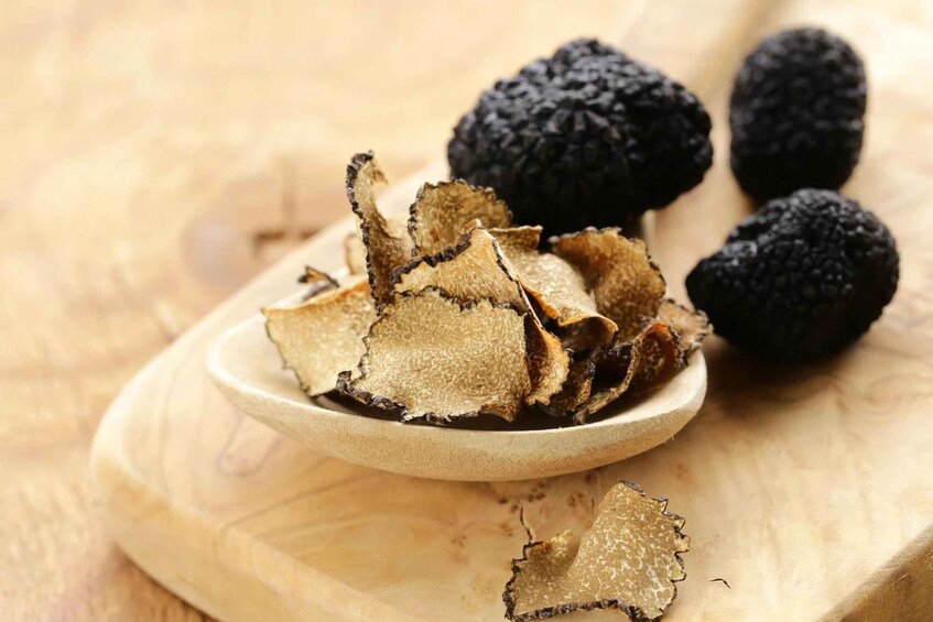A plate of black truffles and sliced truffle shavings on a wooden surface. 3