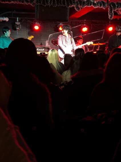 A live music performance with a guitarist on stage, a Marshall amplifier, and a crowd of spectators. 5