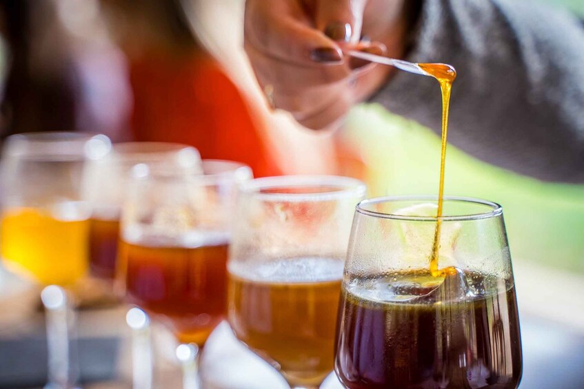 A person pouring a golden liquid into a glass. 1