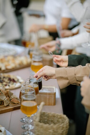 A group of people at a table with glasses of beer, a basket, and food. 4