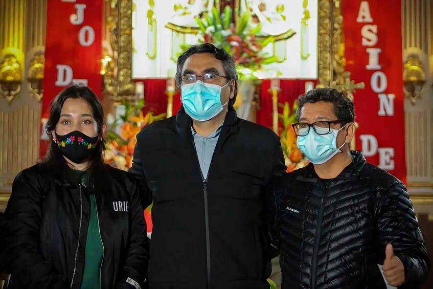 Three individuals standing in front of a red and gold decorated background with the words 'JOD DE ASIONE' visible. 4