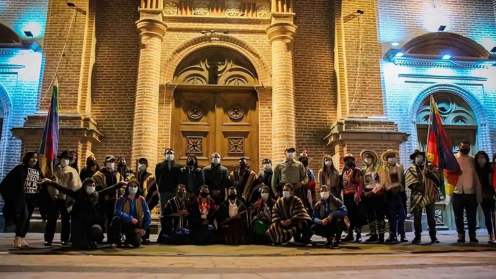 A group of people gathered in front of a historic building with ornate architecture. 1