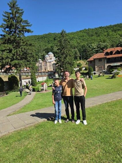 A family standing on a grassy path with a historic building and a hill in the background. 5