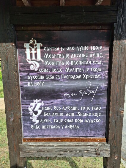 A wooden sign with a handwritten message in Serbian. 3