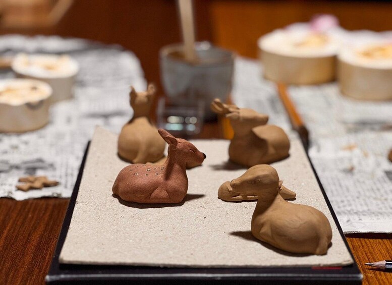 A table with clay sculptures of deer and a glass of water. 5