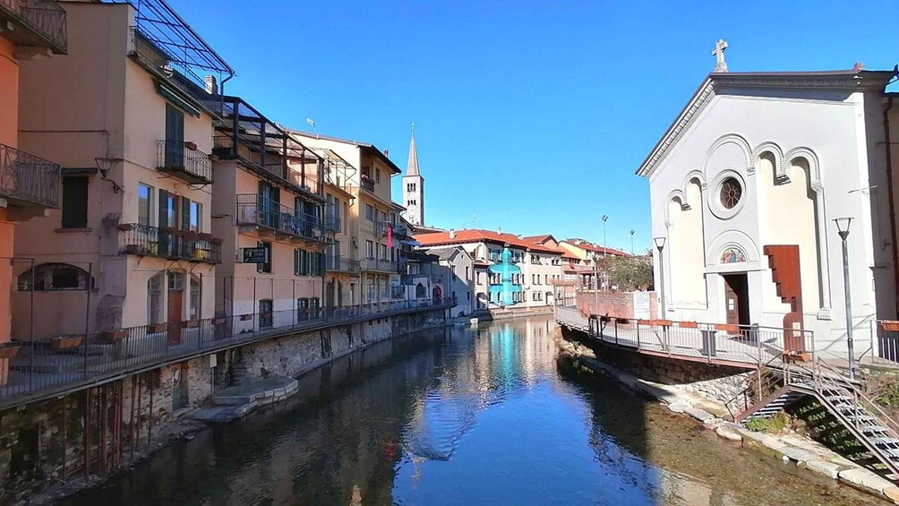 A canal with buildings on either side, a church with a bell tower, and a bridge. 2