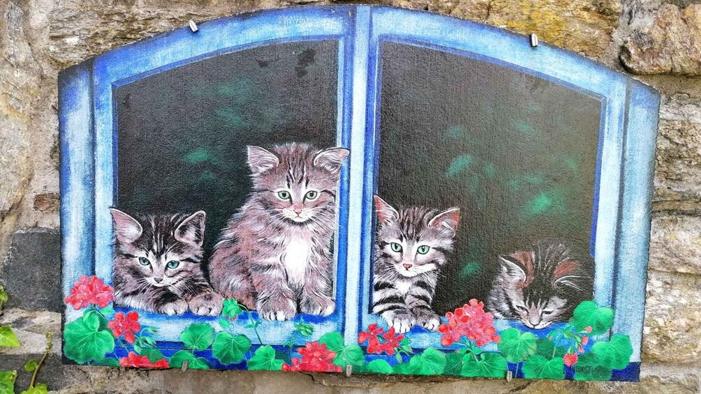 A mural of three kittens on a window sill with flowers. 3