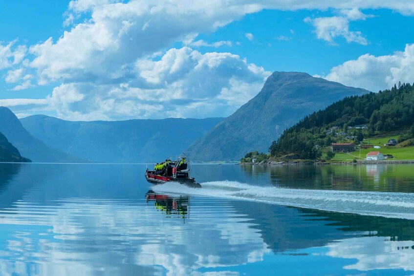 A boat speeding across a calm lake with mountains in the background. 5