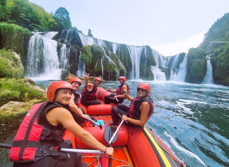 A group of people rafting down a river with multiple waterfalls in the background. 4