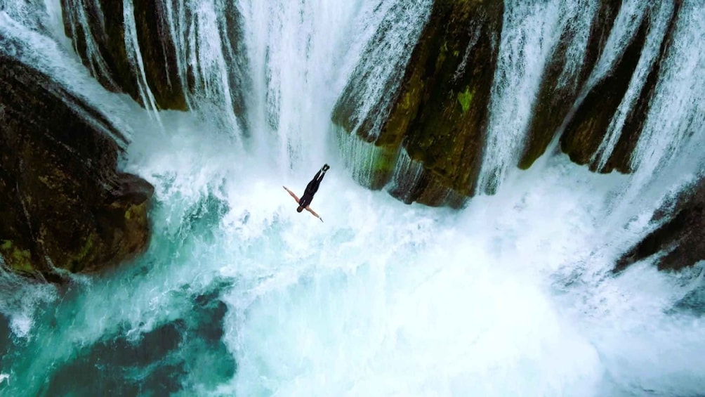A person skydiving over a waterfall. 1