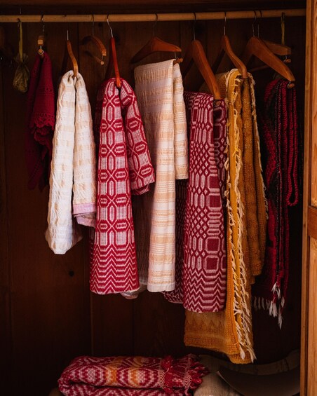 A variety of patterned textiles displayed on wooden hangers. 3